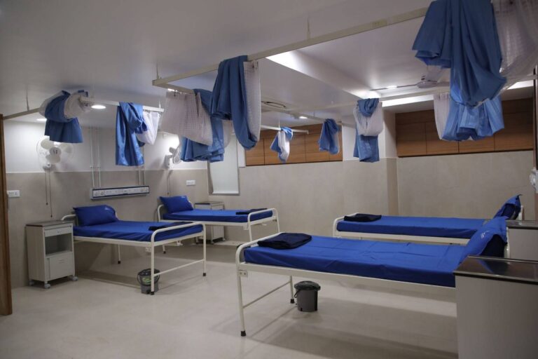 Spacious hospital ward at Care and Cure Multispeciality Hospital with multiple patient beds and privacy curtains side view